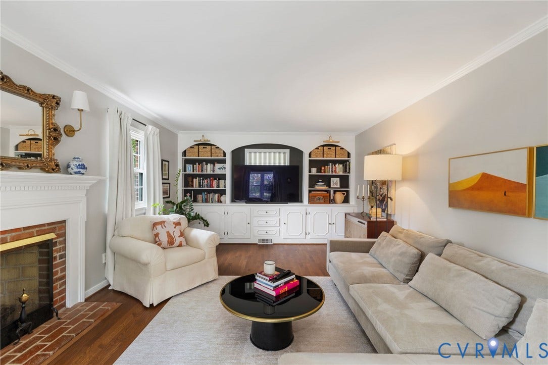 404 Aubery Road, Henrico, VA 23229 Living area featuring refinished hardwood flooring, a brick fireplace with a white mantel, and built-in white cabinetry with shelving