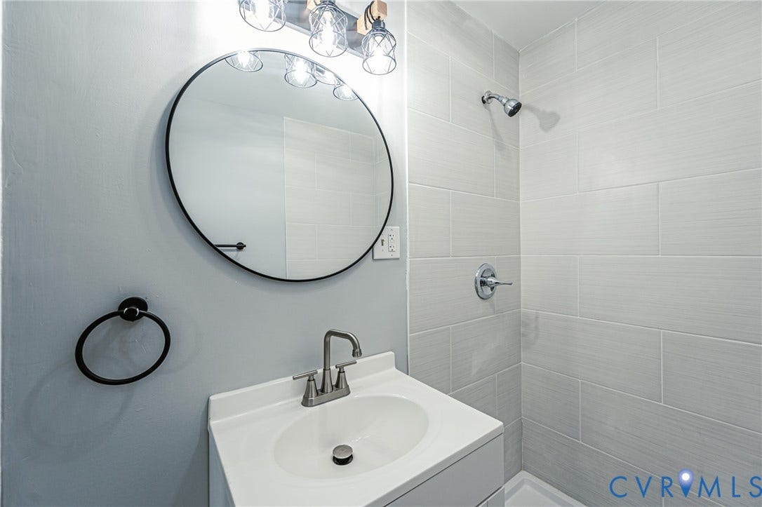 3903 Delmont Street, Henrico, VA 23222 Bathroom featuring a white vanity with integrated sink, brushed nickel faucet, and a circular black-framed mirror
