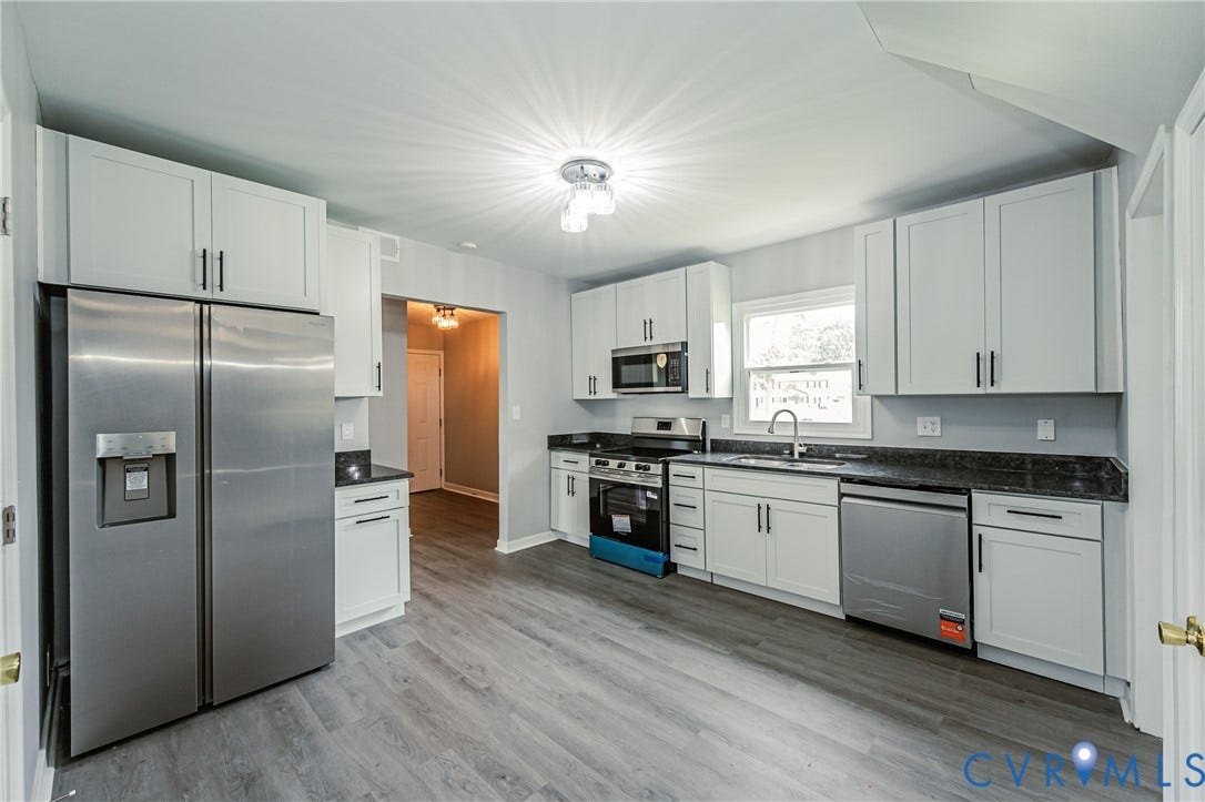 3903 Delmont Street, Henrico, VA 23222 Kitchen featuring wood-finish flooring, white cabinetry with black hardware, dark countertops, and stainless steel appliances including a side-by-side refrigerator, range, microwave, and dishwasher