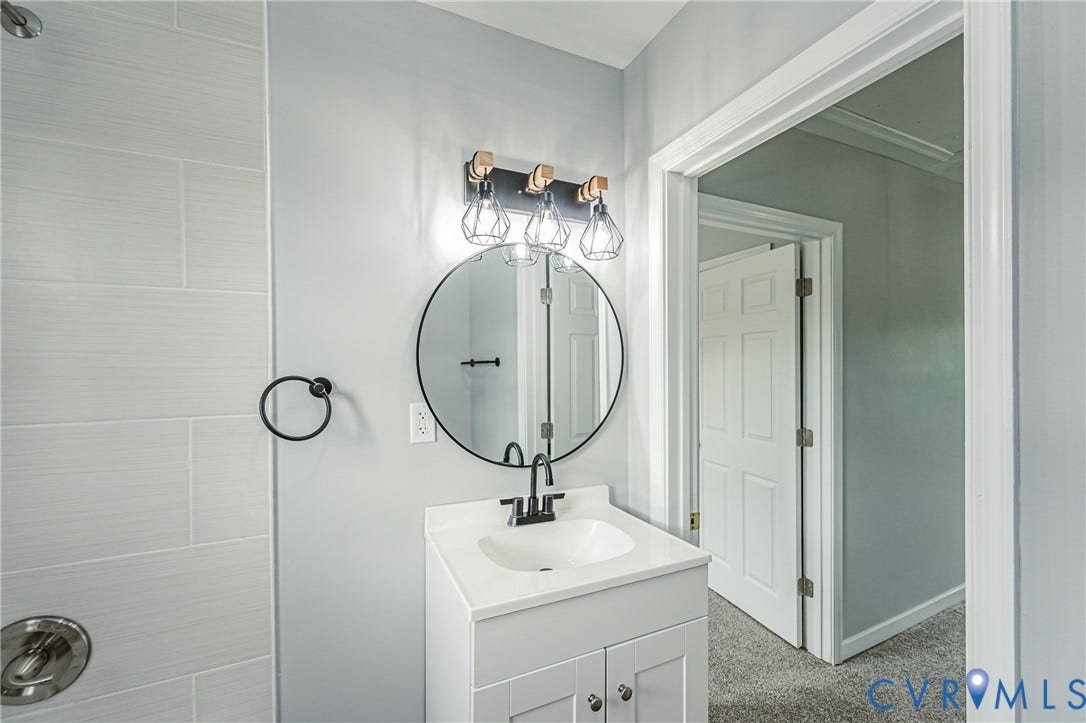 3903 Delmont Street, Henrico, VA 23222 Bathroom featuring a white vanity with integrated sink, circular mirror, and a three-light fixture with geometric cages