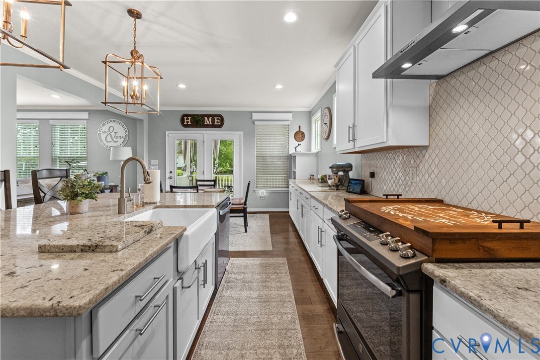 8800 Glen Royal Drive, Chesterfield, VA 23832 Kitchen featuring a spacious island with an integrated farmhouse sink, light-toned countertops, white cabinetry, a patterned tile backsplash, and stainless steel appliances
