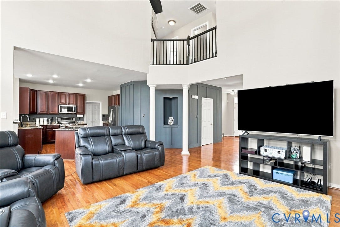 5713 Kings Grove Drive, Kings Grove, Chesterfield, VA 23832 Open-concept living area featuring high ceilings, wood-finish flooring, a kitchen with dark wood cabinetry and stainless steel appliances, and an upper-level balcony with a black railing