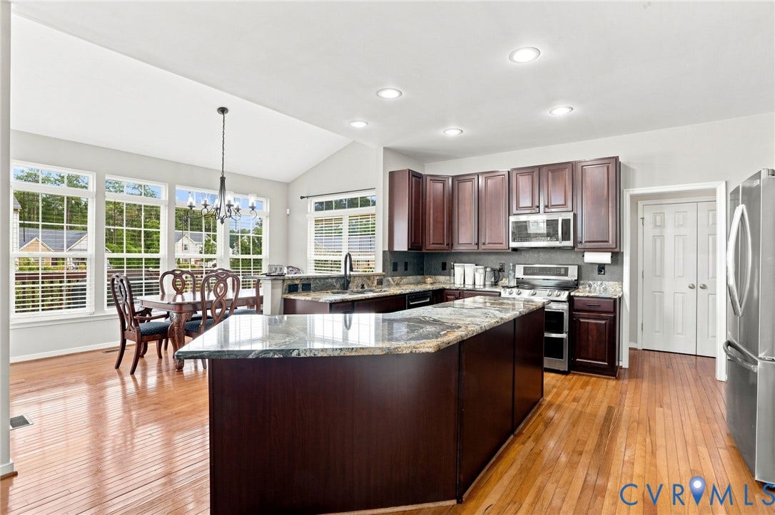 5713 Kings Grove Drive, Kings Grove, Chesterfield, VA 23832 Open-concept kitchen featuring an oversized island with countertop seating, wood-finish flooring, dark wood cabinetry, stainless steel appliances, and a vaulted ceiling