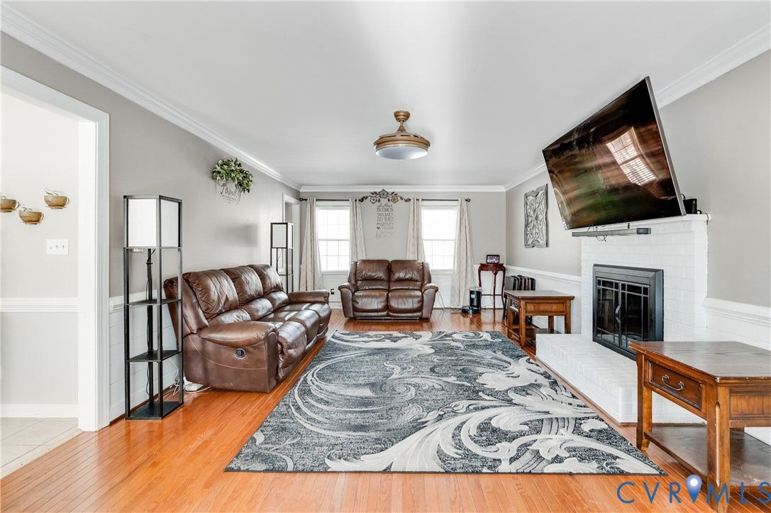 11611 Riverpark Way, Chesterfield, VA 23838 Spacious living area featuring wood-finish flooring, crown molding, and a white brick fireplace