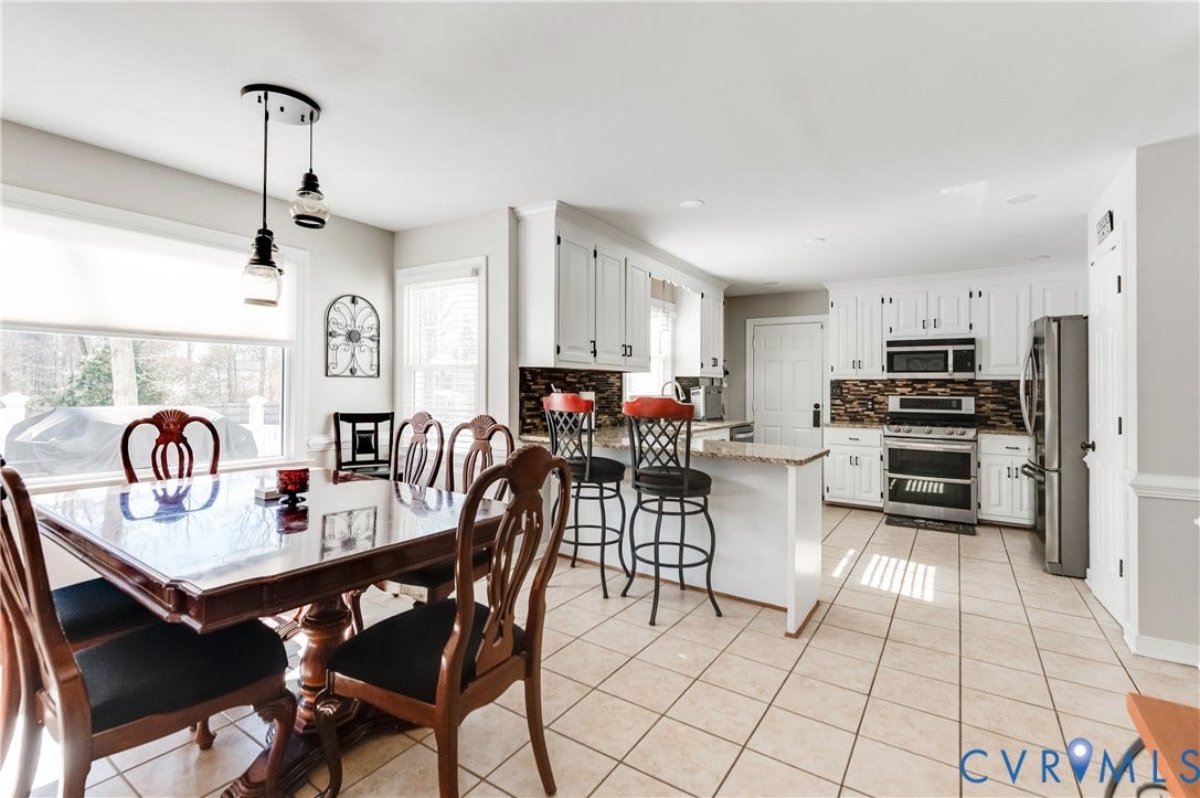 11611 Riverpark Way, Chesterfield, VA 23838 Open-concept kitchen and dining area featuring ceramic tile flooring, white cabinetry with dark hardware, stainless steel appliances, and a kitchen island with granite-style countertop
