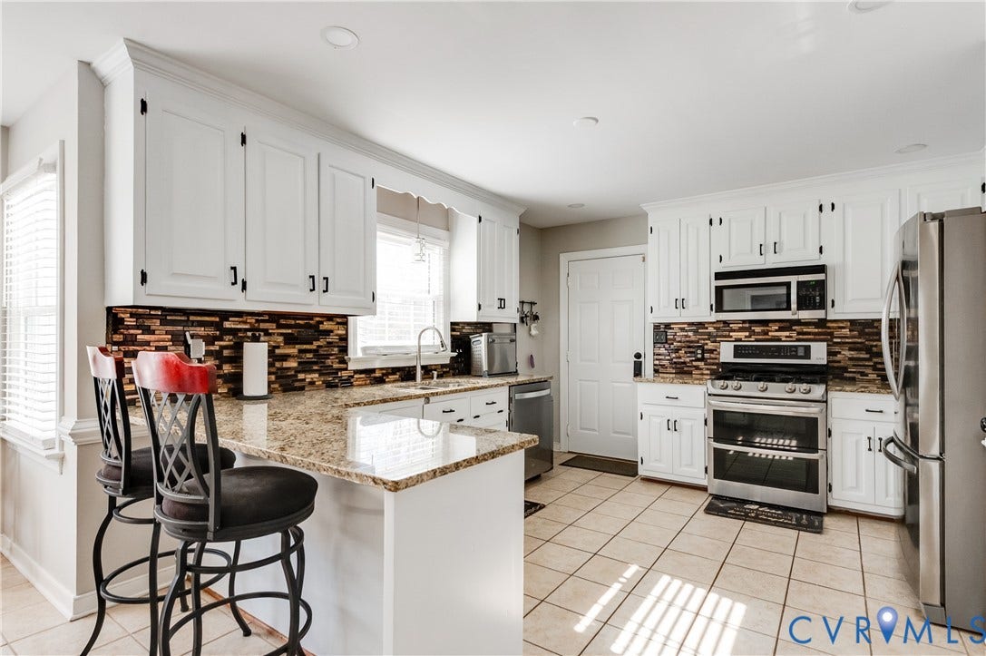 11611 Riverpark Way, Chesterfield, VA 23838 Kitchen featuring white cabinetry with dark hardware, granite countertops, a mosaic tile backsplash, stainless steel appliances, and tile flooring