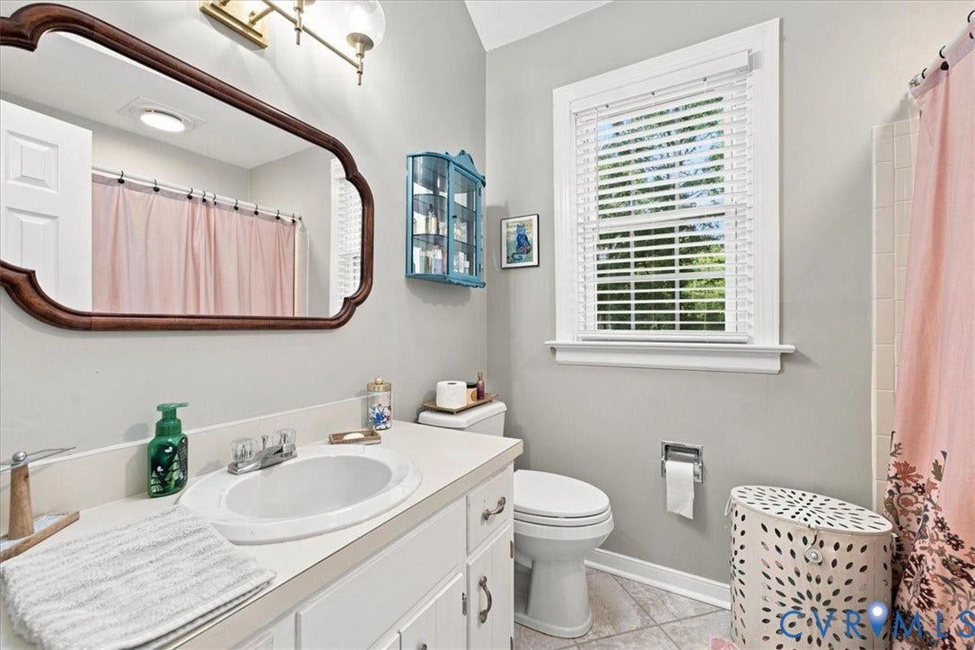 10204 Steuben Drive, Henrico, VA 23060 White vanity with an integrated sink, polished chrome faucet, and decorative wood-frame mirror