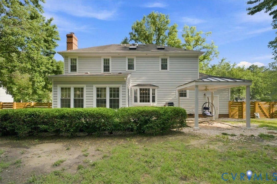 10204 Steuben Drive, Henrico, VA 23060 Rear exterior featuring light-toned siding, a brick chimney, multiple windows, a bay window, and a covered patio area with a metal roof