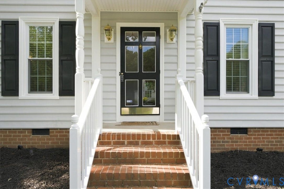 10204 Steuben Drive, Henrico, VA 23060 Inviting front entry featuring a black multi-pane door, flanking windows with dark shutters, white siding, and brick steps with white railings