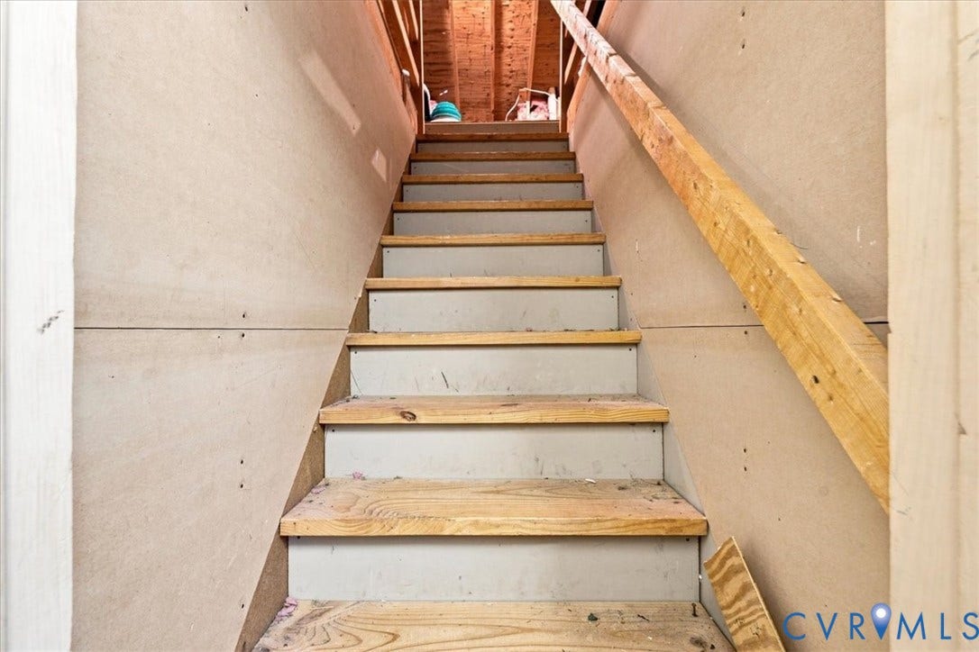 10204 Steuben Drive, Henrico, VA 23060 Unfinished staircase with wood-finish treads and risers, featuring an exposed wood handrail and unfinished wall panels