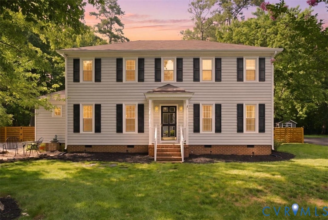 10204 Steuben Drive, Henrico, VA 23060 Two-story colonial residence featuring light-colored siding, dark shutters, a front porch entry with white railings, and a prominent green lawn