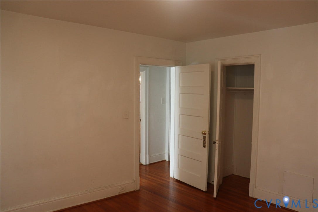 1119 W Grace Street, The Fan District, Richmond, VA 23220 Interior room featuring wood-finish flooring, white walls, white baseboards, and a white paneled door with brass hardware