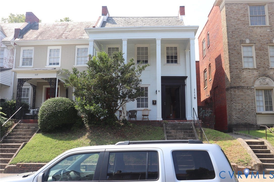 1119 W Grace Street, The Fan District, Richmond, VA 23220 White facade with portico featuring four columns, a dark entry door, and a grassed front yard