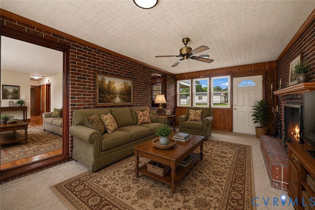 5002 Glendale Avenue, Dinwiddie, VA 23803 Brick accent wall, wood-paneled fireplace, multi-pane windows, ceiling fan, and a white entrance door