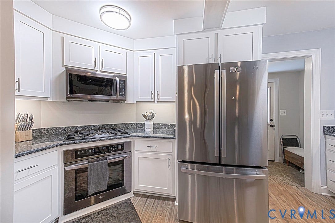 501 Pelham Drive, Richmond, VA 23222 Modern kitchen featuring white shaker cabinetry, stainless steel appliances, dark stone countertops, and wood-finish flooring