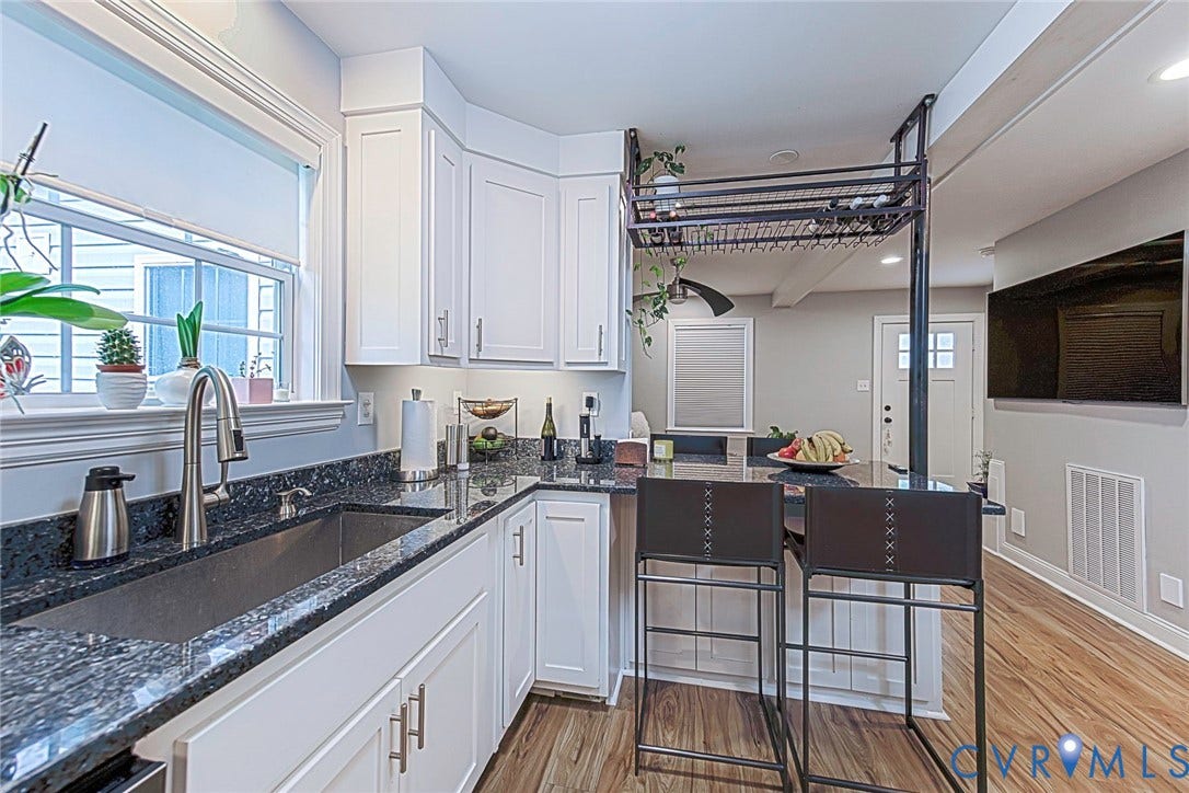 501 Pelham Drive, Richmond, VA 23222 Kitchen featuring white cabinetry, granite countertops, a stainless steel sink, wood-finish flooring, and a breakfast bar with overhead storage