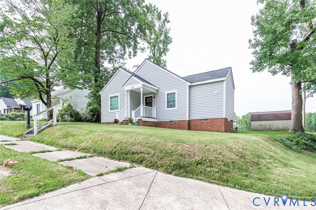 501 Pelham Drive, Richmond, VA 23222 Light gray siding exterior with a dark gray shingle roof, white columned porch, brick foundation, and an expansive front lawn