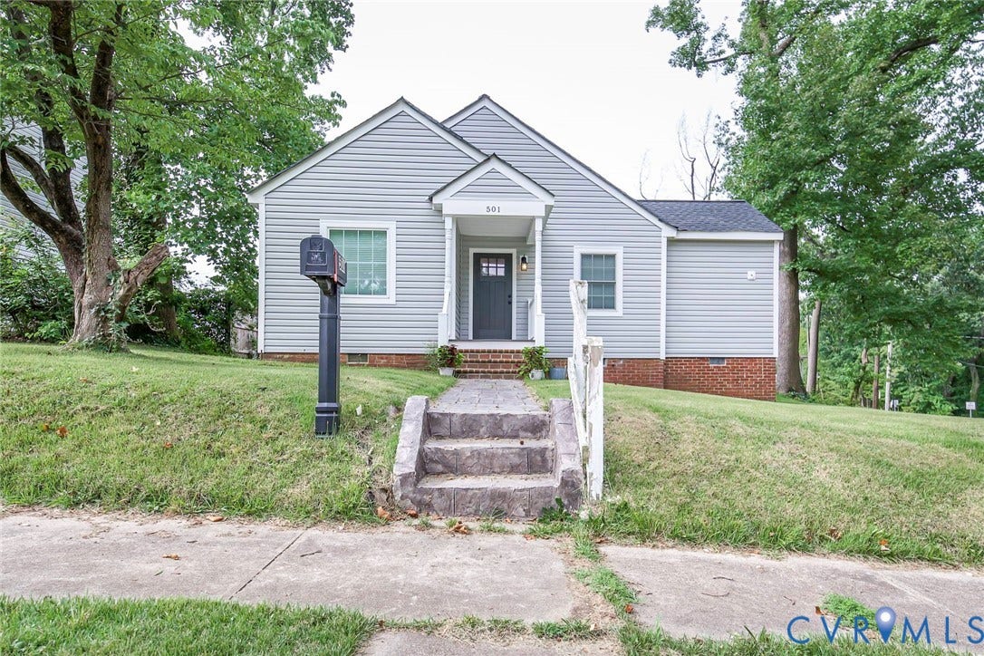501 Pelham Drive, Richmond, VA 23222 Cottage-style home featuring light gray siding, dark gray entry door with glass panel, and a covered porch