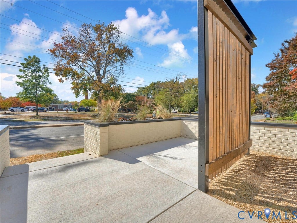 4506 1/2 Grove Avenue, Munford On Grove, Richmond, VA 23221 Exterior space featuring a wood-slat privacy screen, a concrete patio, and a raised planter with brick-veneer siding