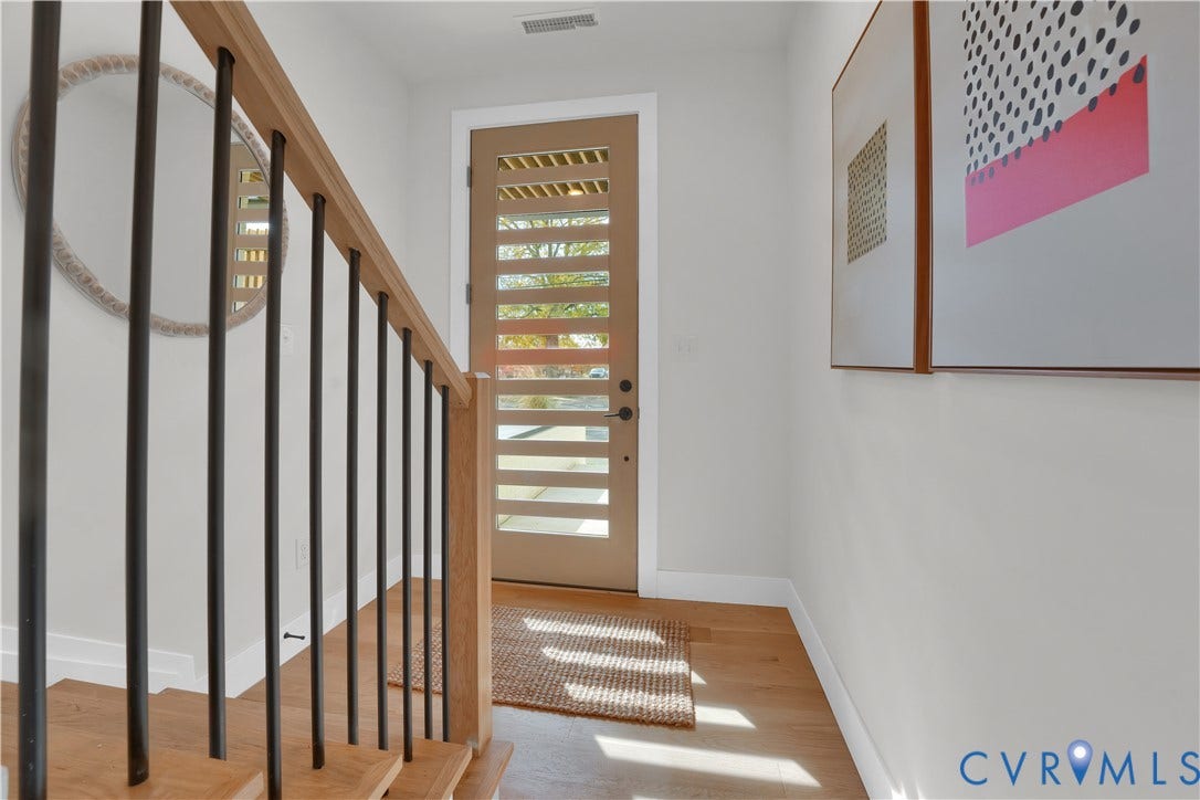 4506 1/2 Grove Avenue, Munford On Grove, Richmond, VA 23221 Entryway featuring a modern wood door with frosted glass panels, wood-finish flooring, and a contemporary staircase with wood handrails and black metal balusters
