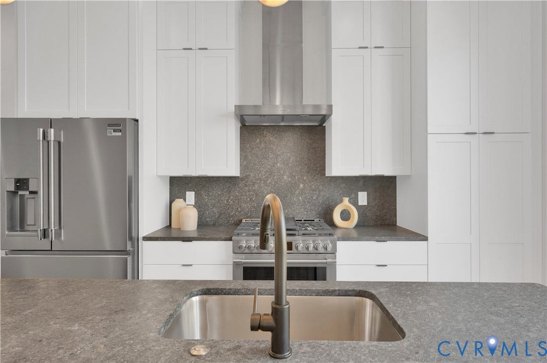 4506 1/2 Grove Avenue, Munford On Grove, Richmond, VA 23221 Modern kitchen featuring a stainless steel undermount sink with a dark bronze faucet, a gray countertop, white shaker cabinetry, a stainless steel range with a ventilation hood, and a full-size stainless steel refrigerator