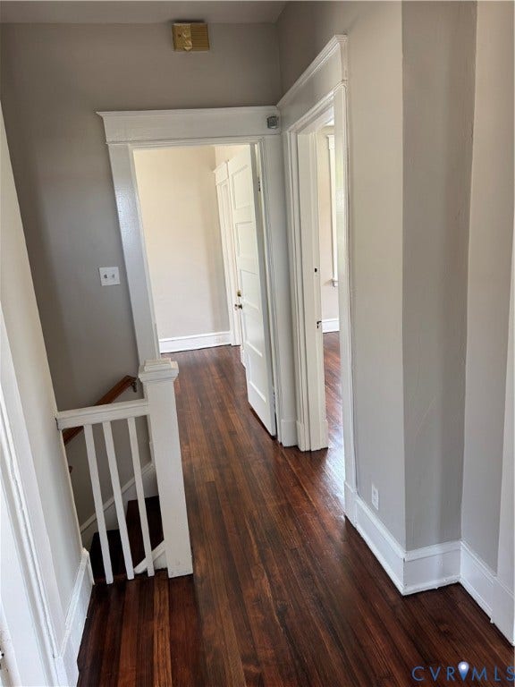 3118 Barton Avenue, Brookland Park, Richmond, VA 23222 Elegant hallway showcasing rich wood-finish flooring, crisp white trim and doors, soft neutral wall tones, and abundant natural light from multiple entry points