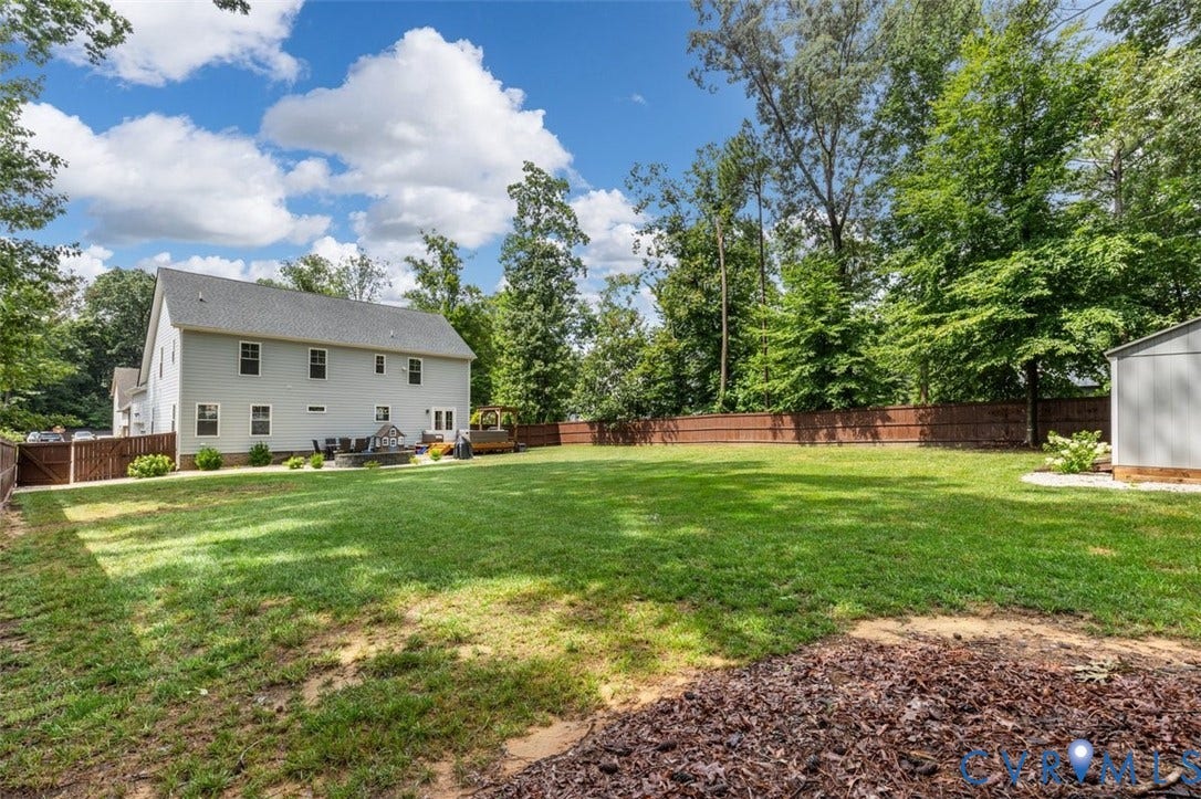 9081 Deerlake Drive, Charming, New Kent, VA 23124 Expansive backyard featuring a manicured lawn, a privacy fence, and mature trees