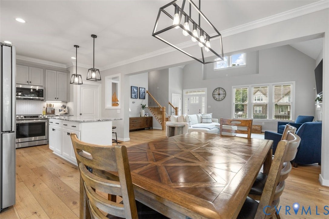 9081 Deerlake Drive, Charming, New Kent, VA 23124 Open-concept kitchen and dining area featuring light wood-finish flooring, a kitchen island with pendant lighting, stainless steel appliances, and a vaulted ceiling with a large window in the family room