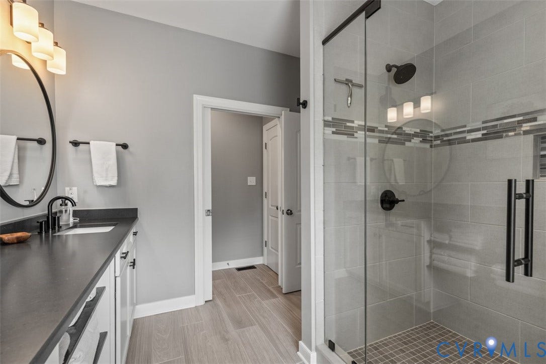 9081 Deerlake Drive, Charming, New Kent, VA 23124 Primary bathroom featuring a frameless glass shower enclosure, double vanity with granite countertop, and updated fixtures