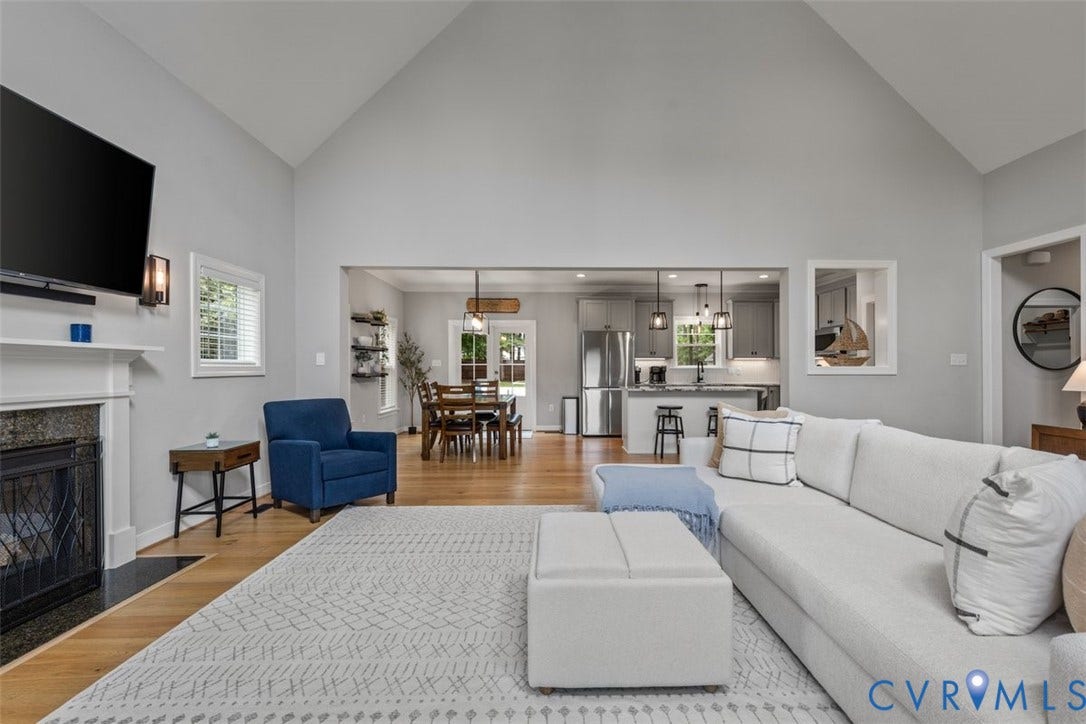 9081 Deerlake Drive, Charming, New Kent, VA 23124 Cathedral ceilings enhance this open-concept living space, featuring a fireplace with a stone surround and white mantel, LVP flooring, and recessed lighting
