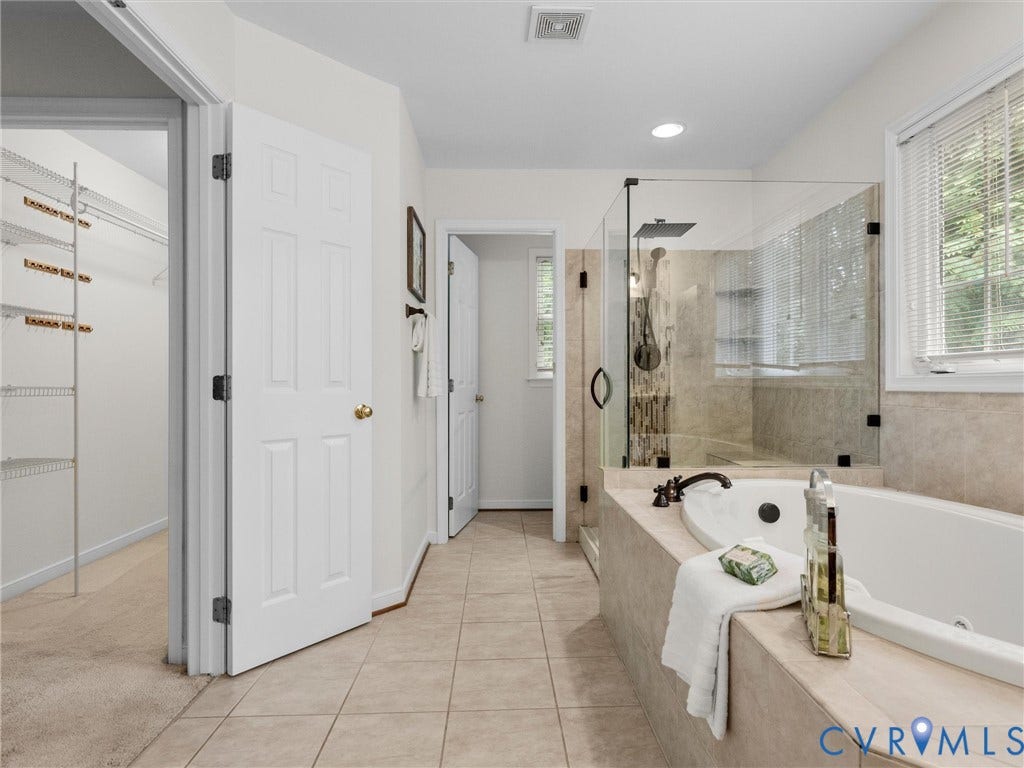 6100 Lilting Branch Way, Moseley, VA 23120 Spacious bathroom featuring a built-in tub, separate glass-enclosed shower, tiled flooring, and a walk-in closet with wire shelving