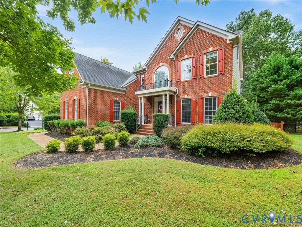 6100 Lilting Branch Way, Moseley, VA 23120 Brick exterior with red shutters, arched window, front porch with balcony, and mature landscaping