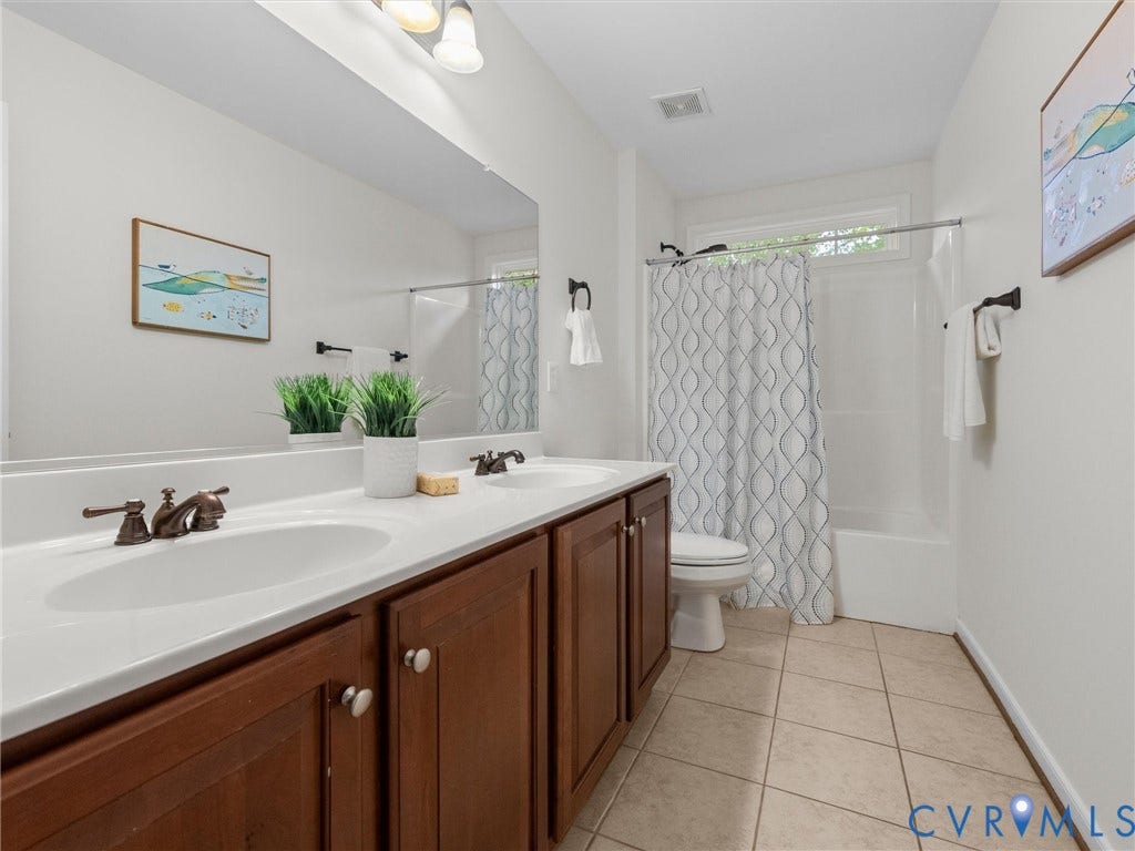 6100 Lilting Branch Way, Moseley, VA 23120 Double vanity with white countertop, integrated sinks, and bronze-finish fixtures