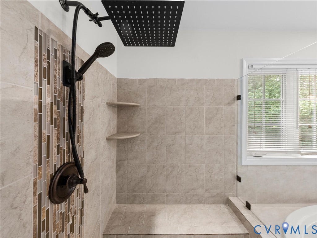 6100 Lilting Branch Way, Moseley, VA 23120 Walk-in shower featuring a rainfall showerhead, handheld shower fixture, and tiled walls with decorative mosaic accents