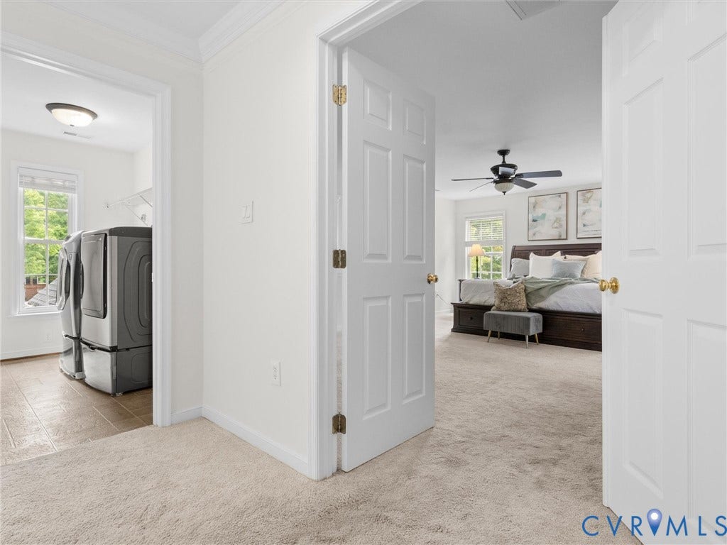 6100 Lilting Branch Way, Moseley, VA 23120 Spacious primary suite with carpeted flooring, ceiling fan, and abundant natural light from multiple windows