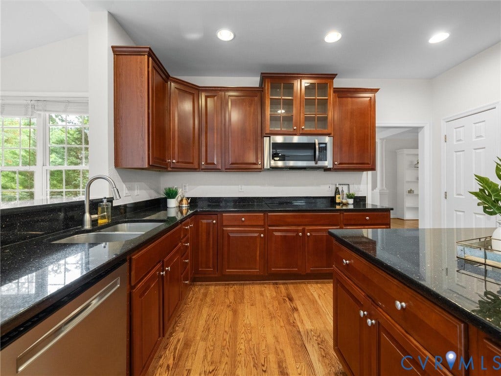 6100 Lilting Branch Way, Moseley, VA 23120 Kitchen featuring wood-finish flooring, dark stone countertops, wood cabinetry, stainless steel appliances, and a vaulted ceiling