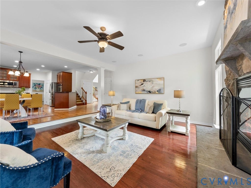 6100 Lilting Branch Way, Moseley, VA 23120 Hardwood flooring, stone fireplace, ceiling fan, recessed lighting, and kitchen with dark wood cabinetry