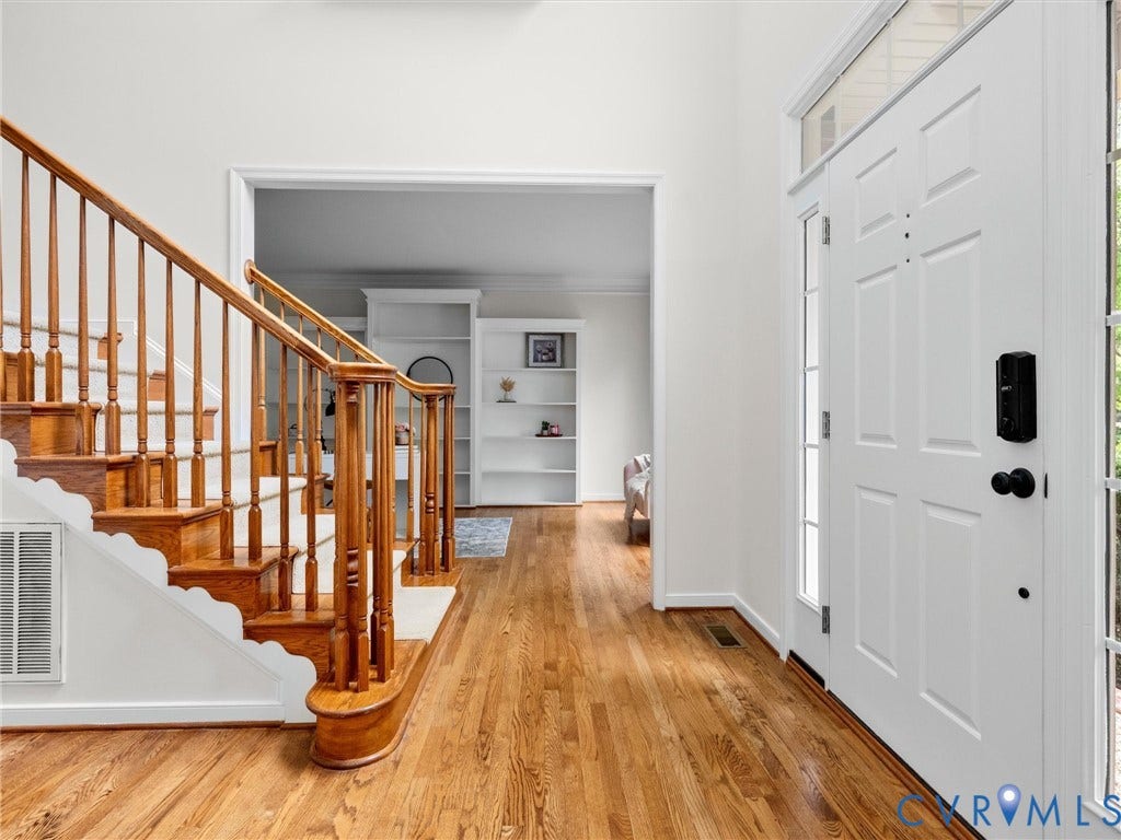6100 Lilting Branch Way, Moseley, VA 23120 Hardwood flooring throughout the entry, staircase with wood banister and white risers, white paneled entry door with sidelights, and transoms