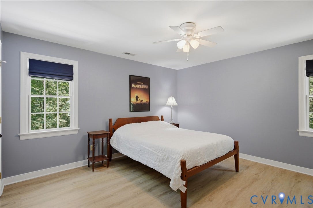 1915 Norwood Creek Drive, Powhatan, VA 23139 Room featuring light-toned wood-finish flooring, two large windows with white trim, and a ceiling fan with integrated lighting