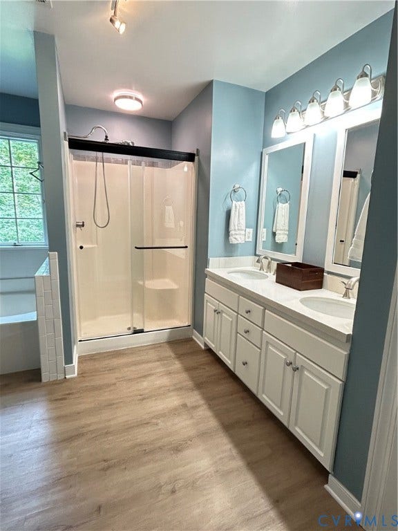1915 Norwood Creek Drive, Powhatan, VA 23139 New double sink with white cabinetry and integrated sinks, wood-finish flooring, glass-enclosed shower, built-in bathtub, and dual mirrors with vanity lighting