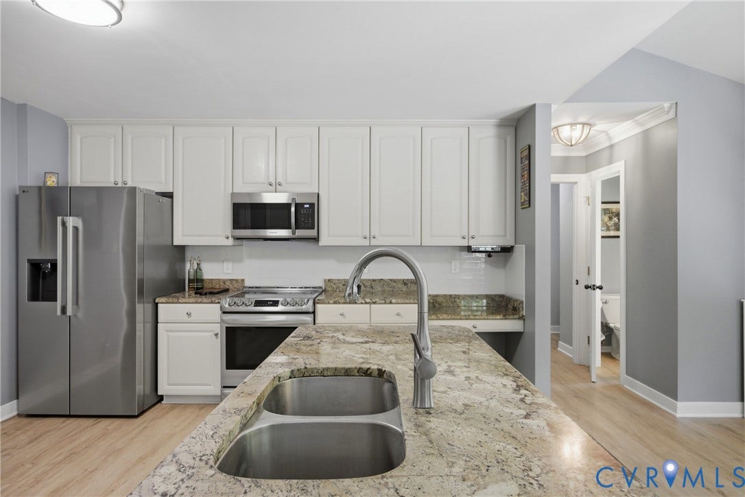 1915 Norwood Creek Drive, Powhatan, VA 23139 Kitchen featuring an island with a double basin sink and gooseneck faucet, light-toned cabinetry, stainless steel appliances, and wood-finish flooring