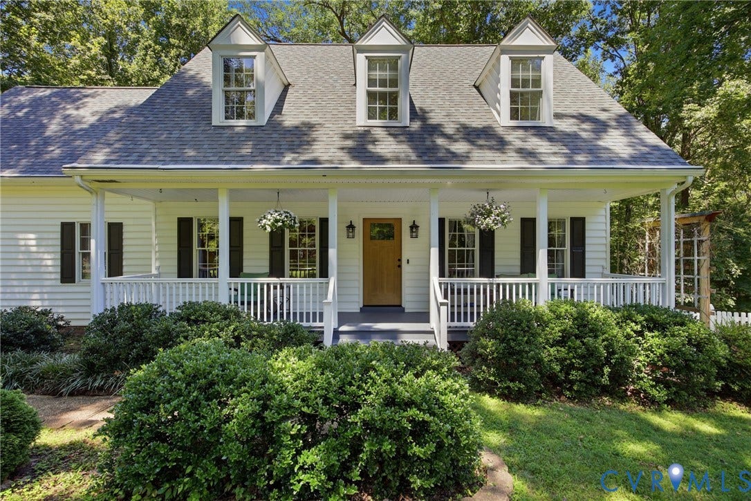 1915 Norwood Creek Drive, Powhatan, VA 23139 White siding residence featuring a covered front porch with white railing, three dormer windows, a light wood-finish front door, and a gray shingle roof