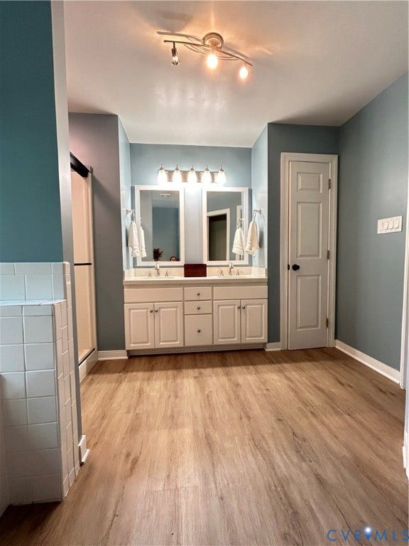 1915 Norwood Creek Drive, Powhatan, VA 23139 New double sink top, with white vanity, wood-finish flooring, track lighting, and a white tiled shower enclosure