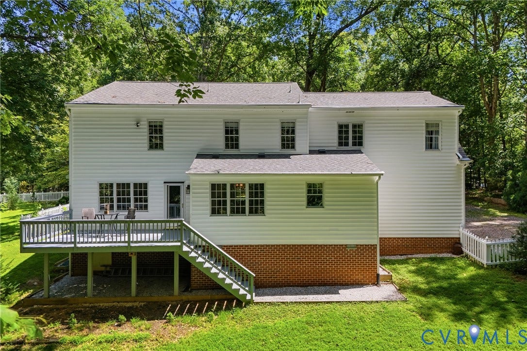 1915 Norwood Creek Drive, Powhatan, VA 23139 Rear exterior featuring white siding, a multi-level deck with stairs, a brick foundation, and a gravel patio area