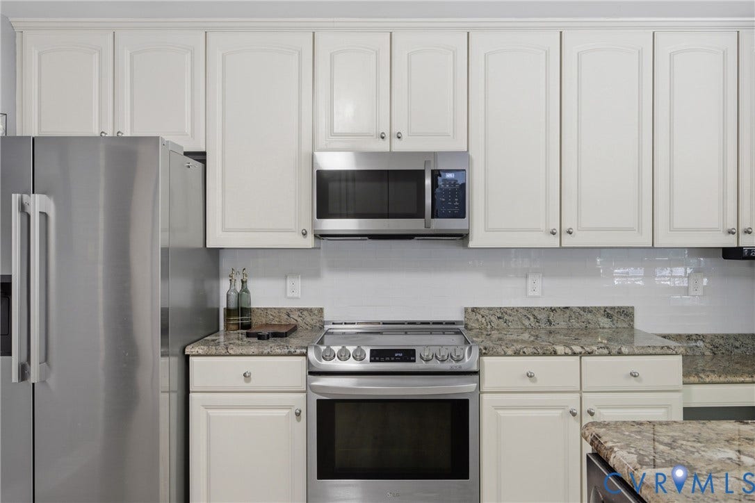 1915 Norwood Creek Drive, Powhatan, VA 23139 Gourmet kitchen with stainless steel appliances, granite countertops, white shaker cabinetry, and a subway tile backsplash