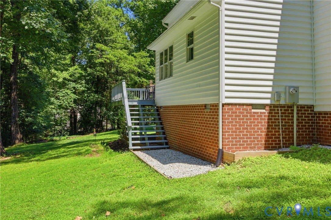 1915 Norwood Creek Drive, Powhatan, VA 23139 Exterior featuring white siding, brick foundation, and a multi-level deck with stairs descending to a gravel path