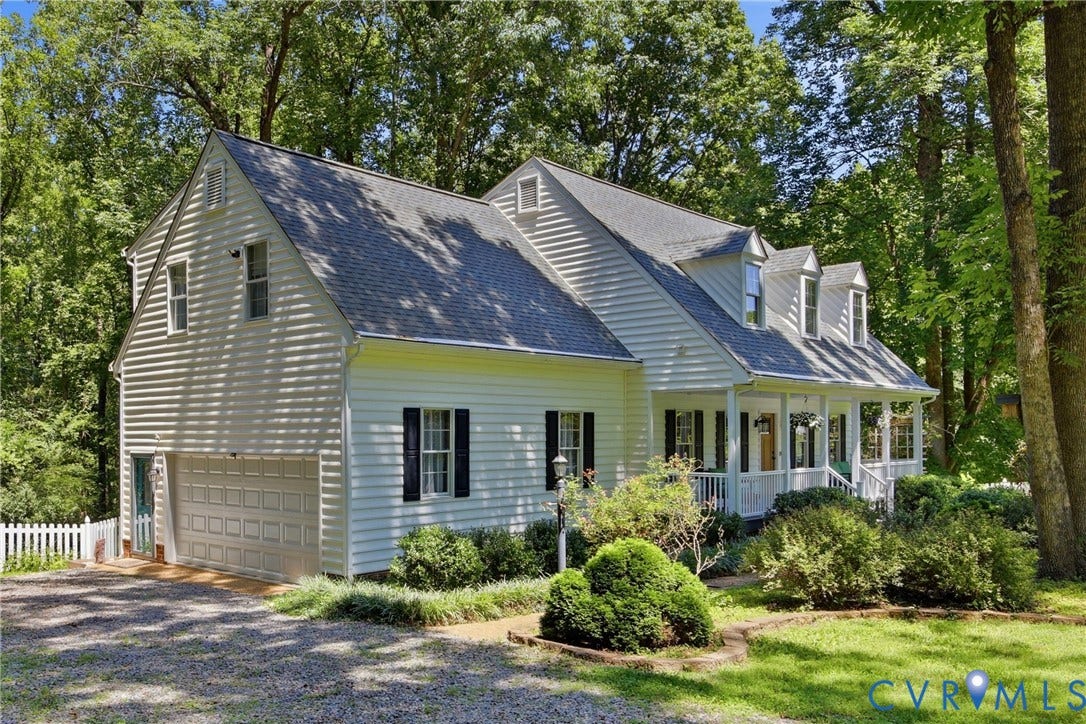 1915 Norwood Creek Drive, Powhatan, VA 23139 White siding residence featuring a covered front porch with white railings, multiple dormer windows, and black louvered shutters