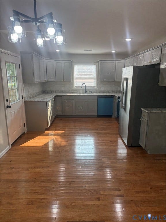 Updated kitchen featuring light grey cabinetry, granite-style countertops, a tile backsplash, and stainless steel appliances