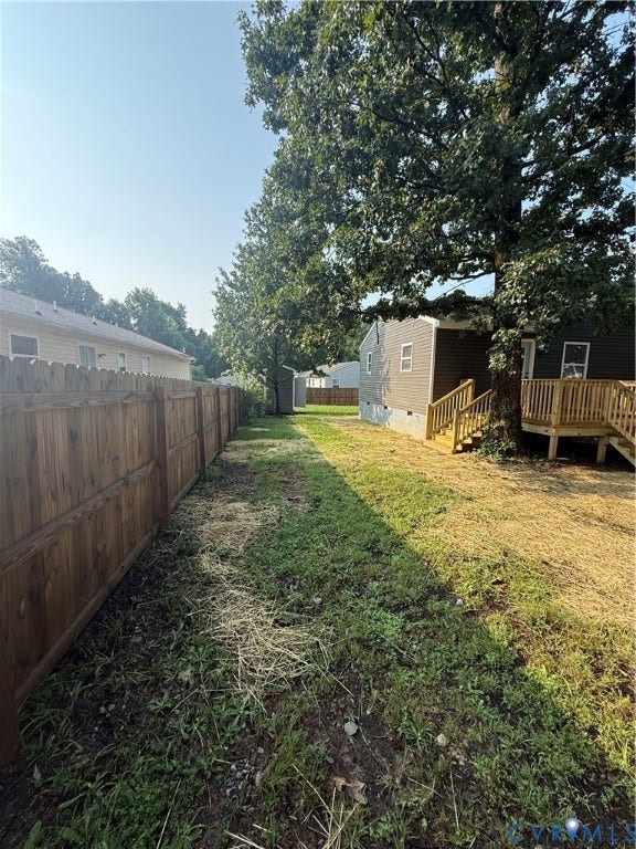 Expansive outdoor space featuring a new wood privacy fence, a newly constructed wood deck with stairs, mature trees, and a storage shed