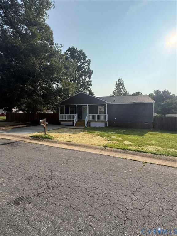 Single-story residence featuring dark siding, a covered front porch with white railings, and a light-colored front door
